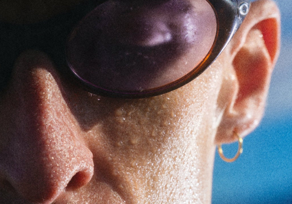 Close-up of a person wearing sunglasses with a blue sky background