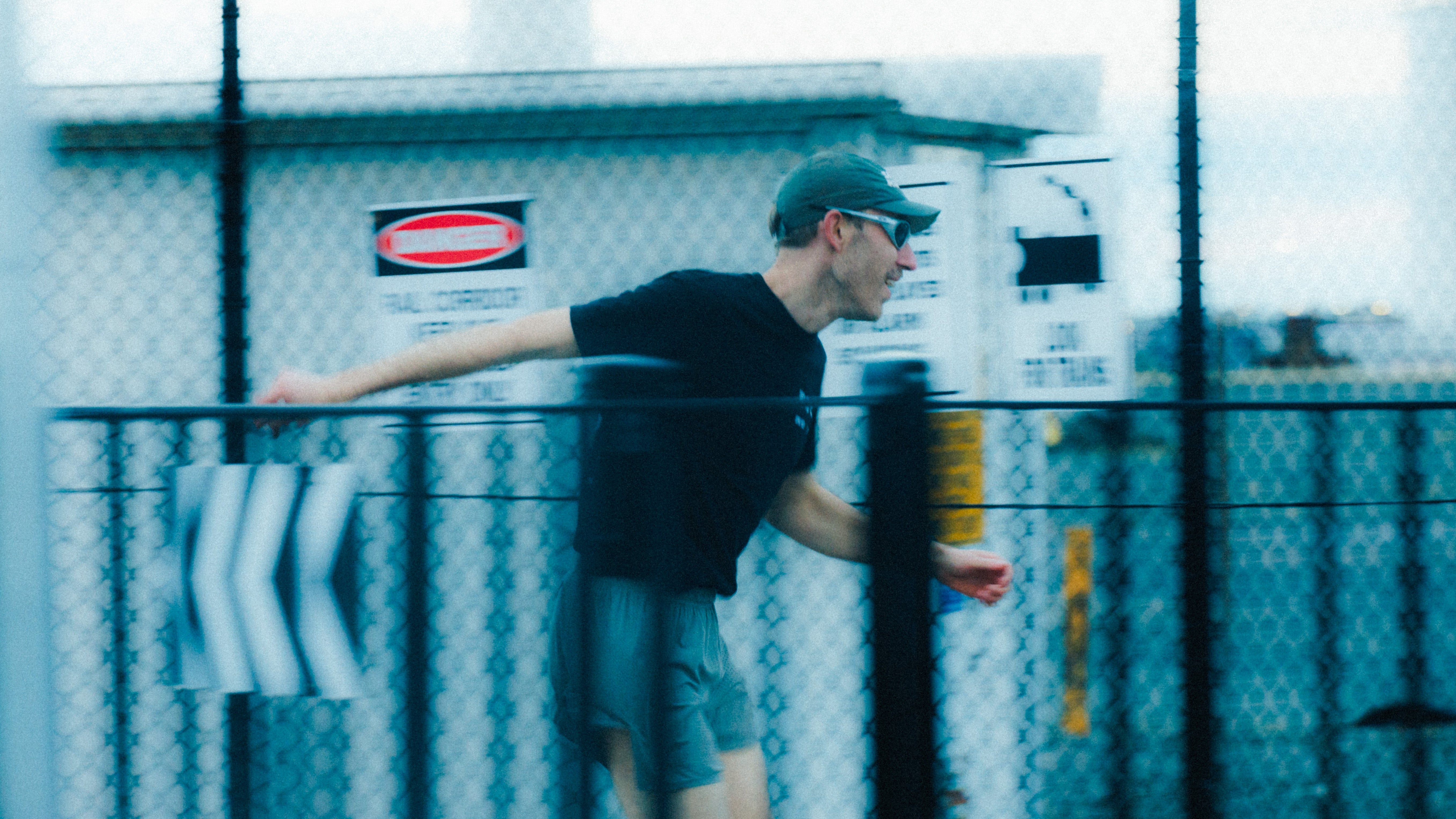 Person running on a track with a fence and building in the background